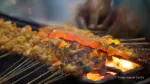 Memanggang sate untuk makanan khas idul adha yang disantap bersama keluarga