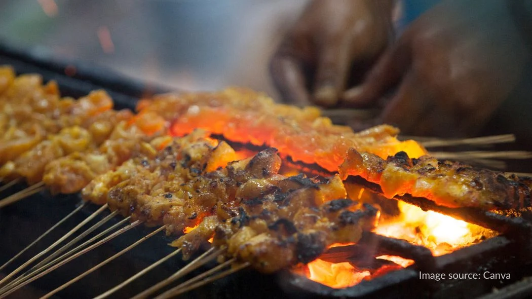 Memanggang sate untuk makanan khas idul adha yang disantap bersama keluarga